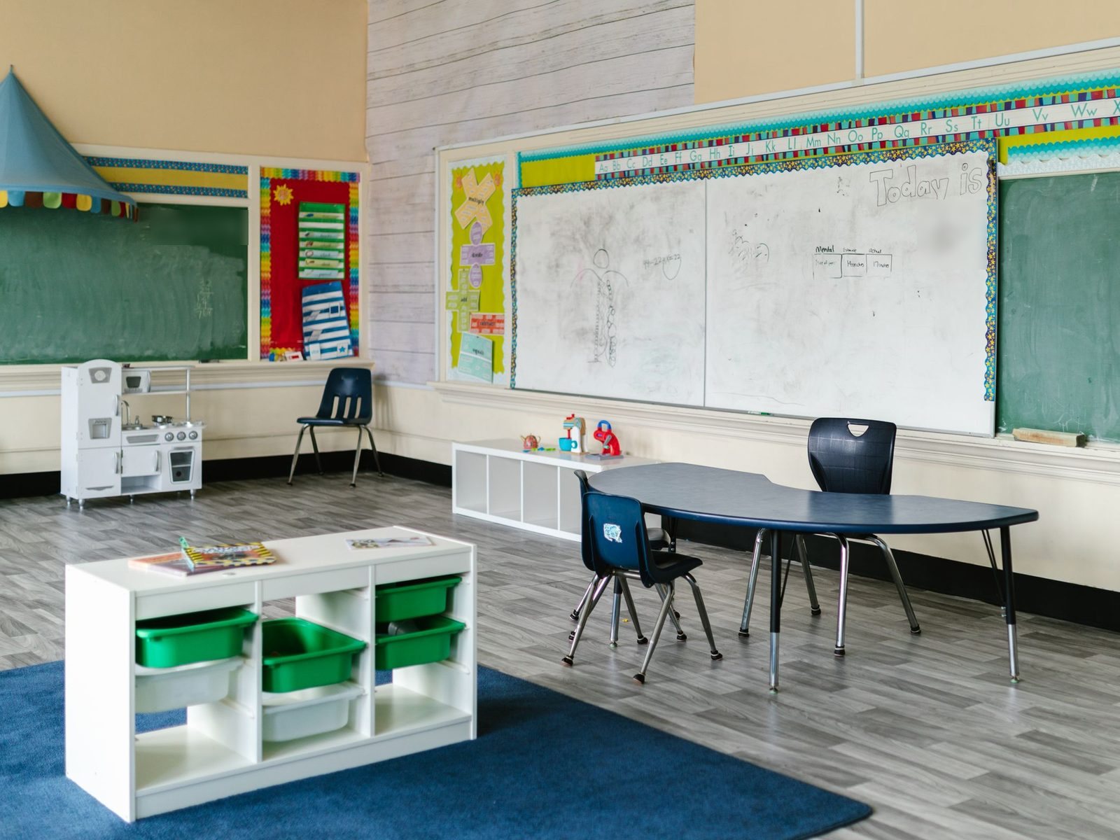 Empty classroom with small chairs, a kidney-shaped table and storage shelves